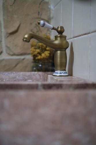 a bathroom sink with a brass water faucet at Casa rural fuentelgato in Huerta del Marquesado