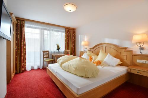 a bedroom with a large white bed with a red carpet at Café-Pension Kaisermann in Ellmau