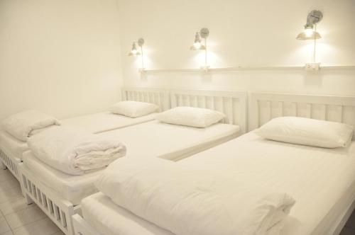 two beds in a room with white sheets and pillows at Zleepinezz Hostel in Phra Nakhon Si Ayutthaya