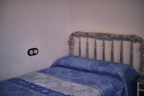 a bedroom with a bed with blue comforter and a bedskirts at Casa rural fuentelgato in Huerta del Marquesado