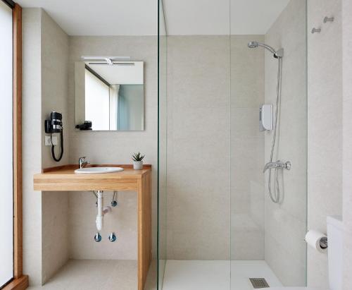 a bathroom with a shower with a sink and a mirror at IRAIPE Estella Rooms Auto Check-in in Estella