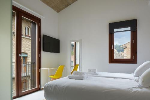 a white bedroom with two beds and a window at IRAIPE Estella Rooms in Estella