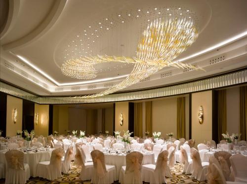 a banquet hall with white tables and chairs and a chandelier at Wyndham Grand Istanbul Europe in Istanbul