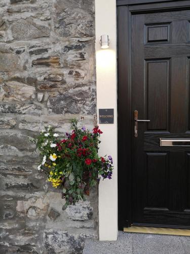 a door with a bouquet of flowers next to a stone wall at Seaview Guesthouse in Mallaig