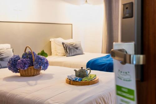 a hotel room with two beds with flowers on a table at Hotel São Miguel in Ponta Delgada