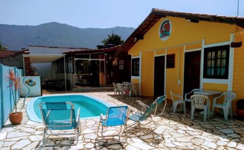a patio with chairs and a pool in front of a house at Chalé Master Caraguatatuba cond Alto Padrão Massaguaçu in Caraguatatuba