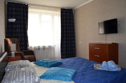 um quarto de hotel com uma cama com almofadas azuis e uma televisão em Standard Brusnika Apartment Shchyukinskaya em Moscovo