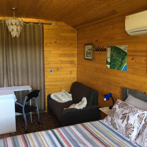 a bedroom with a bed and a couch and a chair at Pousada Cristal Serra in Cambará