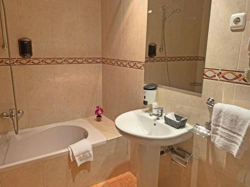 a bathroom with a sink and a bath tub and a mirror at Hotel Antic in Ordino