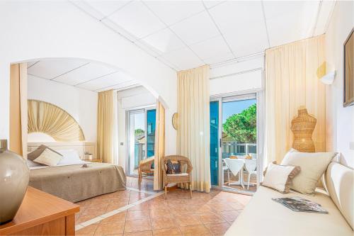 a bedroom with a bed and a room with a table at Hotel Rex in Lignano Sabbiadoro