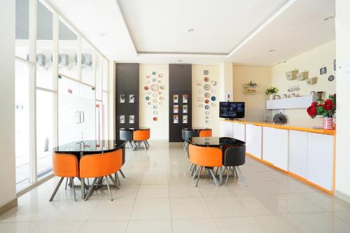 a dining room with orange chairs and a table at Pratisarawirya Guesthouse by ecommerceloka in Surabaya