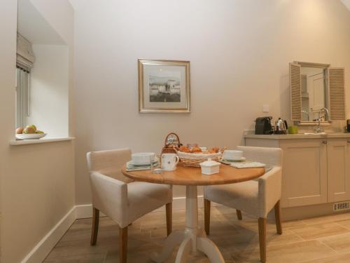 eine Küche mit einem Tisch und Stühlen sowie eine Küche mit einem Waschbecken in der Unterkunft Cow Drove Cottage in Salisbury