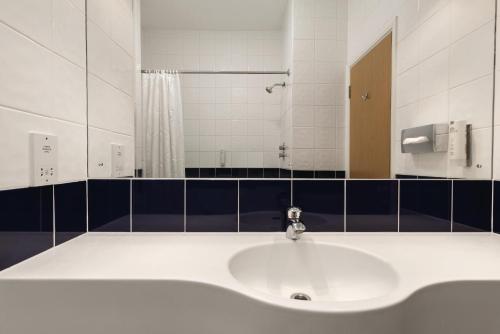 a bathroom with a white sink and a mirror at Days Inn by Wyndham Donington in Castle Donington