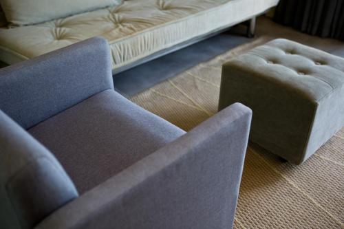 a chair and a stool in a living room with a couch at Ritz Leblon in Rio de Janeiro