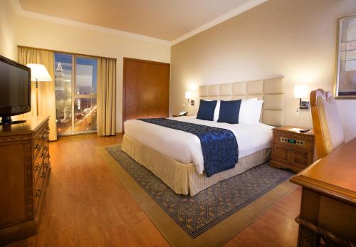 een hotelkamer met een groot bed en een televisie bij Millennium Plaza Downtown Suites in Dubai