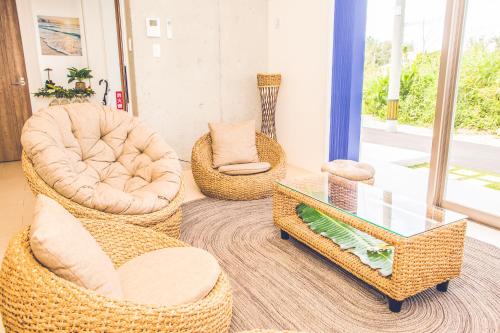 a living room with wicker chairs and a glass table at HALE恩納村 Ys Casa in Onna