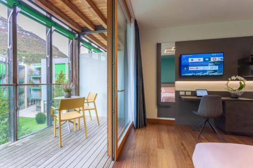 Zimmer mit einem Balkon mit einem Tisch und einem TV. in der Unterkunft Habitat Guest House in Trient