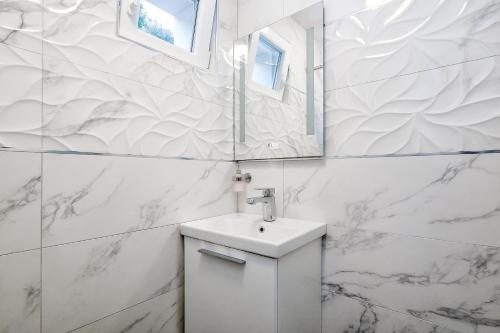 Baño blanco con lavabo y espejo en Holiday home Beyla en Pučišća