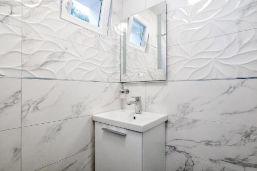 a white bathroom with a sink and a mirror at Holiday home Beyla in Pučišća