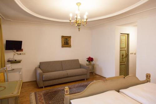 a living room with a couch and a chandelier at Hotel Wilder Mann in Passau