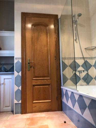 baño con ducha y puerta de madera en Villa La Encina, en Quijas