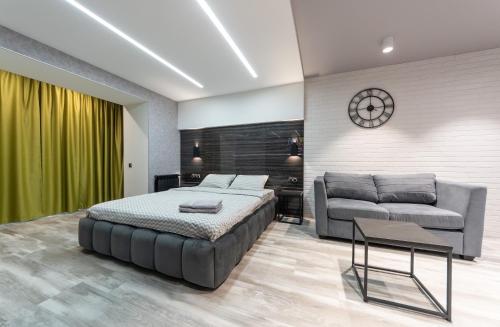 a bedroom with a bed and a couch and a clock at Luxrent Kreshatik Arenacity SkyBar in Kyiv
