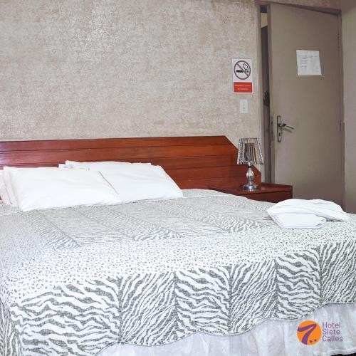 1 dormitorio con cama blanca y cabecero de madera en Hotel 7 Calles, en Santa Cruz de la Sierra