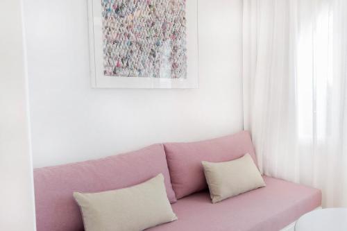 a pink couch with two pillows in a living room at Stelia Mare Boutique Hotel in Naousa