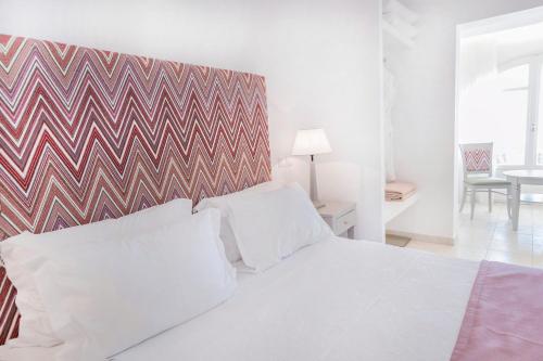 a bedroom with a white bed with a geometric headboard at Stelia Mare Boutique Hotel in Naousa
