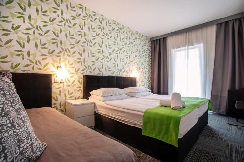 a hotel room with two beds and a green table at Hotel Bio in Koper