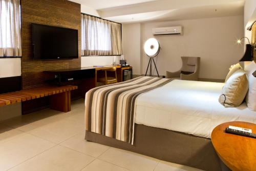 a hotel room with a bed and a flat screen tv at Ritz Leblon in Rio de Janeiro