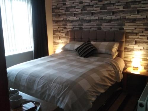 a bedroom with a large bed with a brick wall at 24 Fairfield Road in Uttoxeter