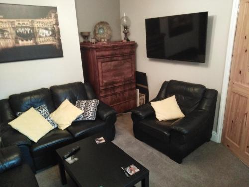 a living room with two leather chairs and a television at 24 Fairfield Road in Uttoxeter