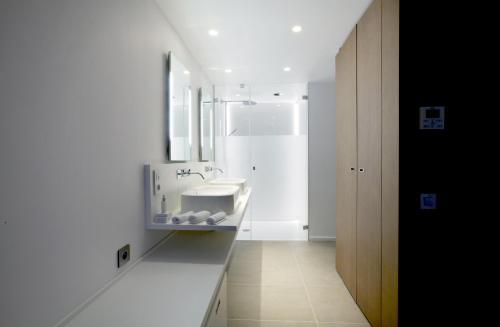 a white bathroom with a sink and a mirror at Hotel C2 in Marseille