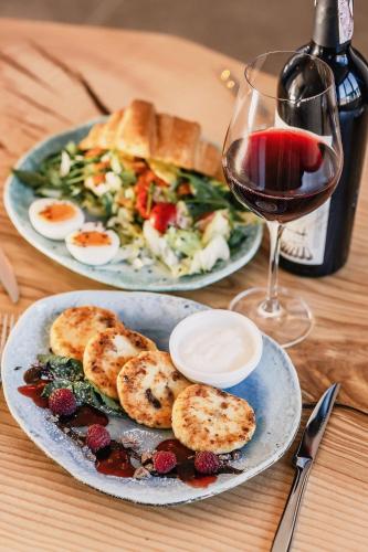 a table with two plates of food and a glass of wine at Sofia Hotel in Rivne