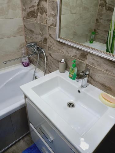 a bathroom with a white sink and a bath tub at ApartLux on Slavskogo 14 in Ustʼ-Kamenogorsk