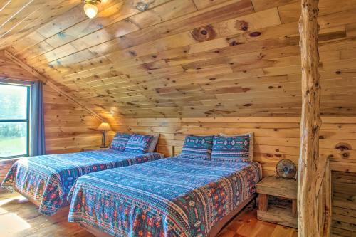 two beds in a log cabin bedroom with wooden walls at Peaceful Pet-Friendly Retreat with Private Hot Tub! in Broken Bow