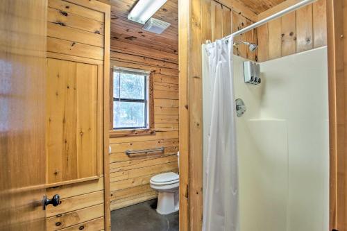 a wooden bathroom with a toilet and a window at Peaceful Pet-Friendly Retreat with Private Hot Tub! in Broken Bow