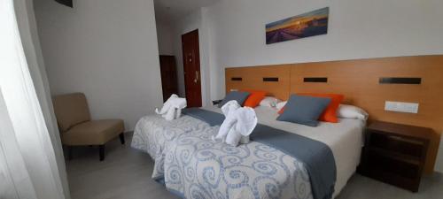 a bedroom with two beds with white towels on them at Pensión Mar in Portomarin