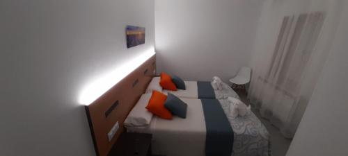 a bedroom with a bed with orange and blue pillows at Pensión Mar in Portomarin