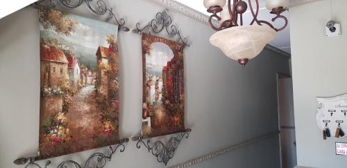 two paintings hanging on a wall with a chandelier at Lamon Guesthouse in Kroonstad