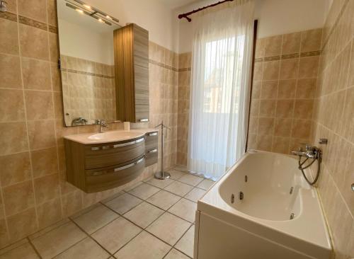 W łazience znajduje się wanna, umywalka i lustro. w obiekcie Ville sul Mare w mieście Marina di Grosseto