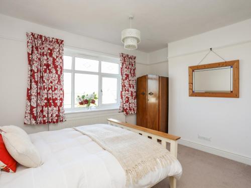 a bedroom with a bed and a window and a mirror at Bryngwyn - Trearddur Bay in Holyhead