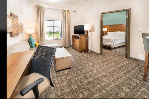 a hotel room with a bed and a desk and a mirror at Staybridge Suites Florence - Cincinnati South by IHG in Florence