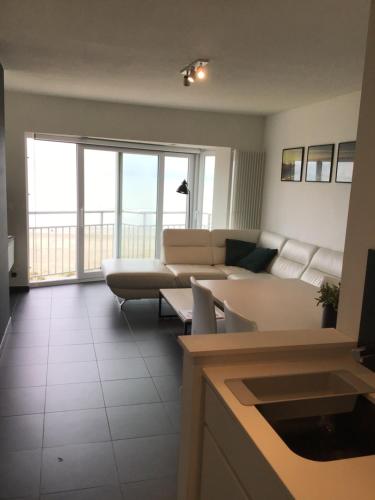 sala de estar con sofá blanco y ventana grande en Marjolaine Zeezicht - Nieuwpoort-bad met GRATIS garagebox en Nieuwpoort