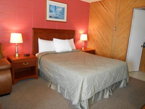 a bedroom with a bed and two night stands with two lamps at Aquarius Motel in Perth