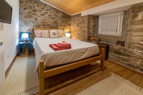 een slaapkamer met een bed in een kamer met stenen muren bij O Palheiro - Vista Panorâmica e Jacuzzi in Sobreira Formosa