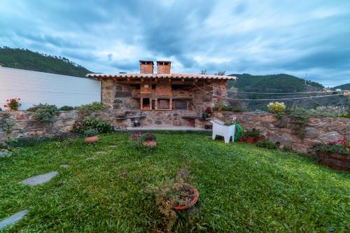 a stone house in a yard with a green lawn at O Palheiro - Vista Panorâmica e Jacuzzi in Sobreira Formosa
