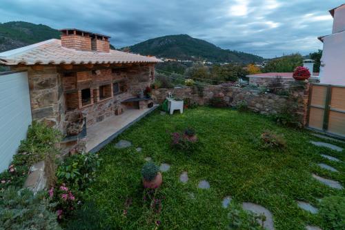a backyard of a stone house with a garden at O Palheiro - Vista Panorâmica e Jacuzzi in Sobreira Formosa