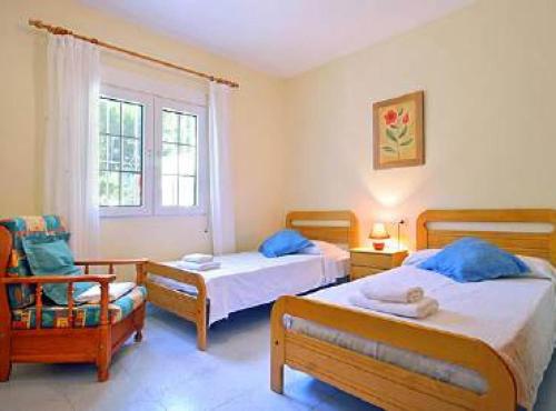 1 dormitorio con 2 camas, silla y ventana en Villa Miguel - Plusholidays, en Benissa